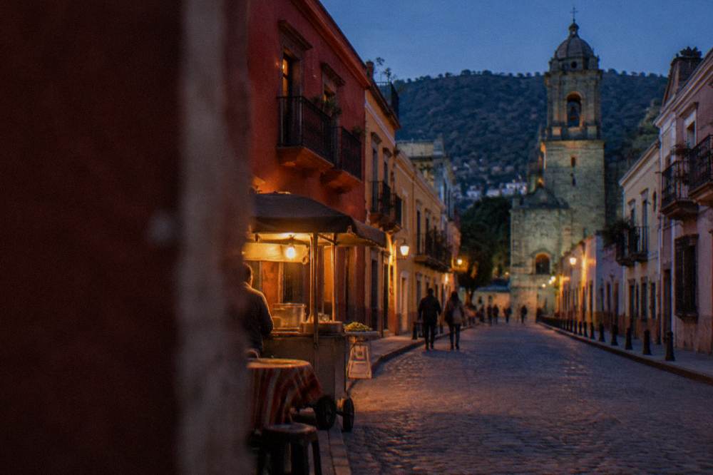 An evening street scene in Oaxaca City with warm lighting over a food stall