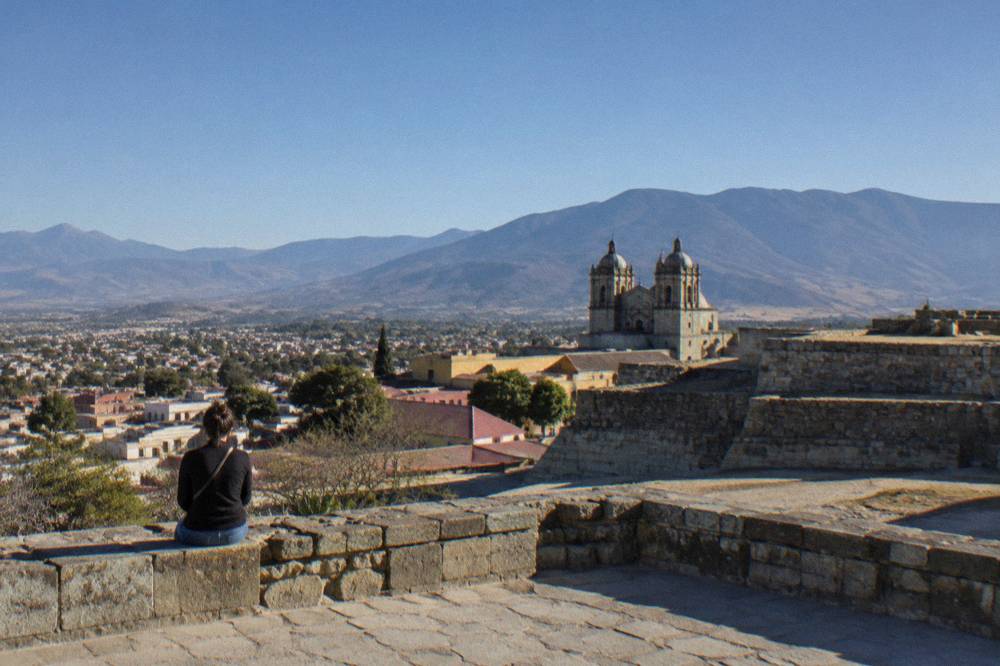 A stone terrace of an archaeological site above a valley with mountains behind